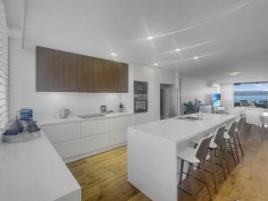 eine Küche mit weißen Schränken und einer Bar mit Stühlen in der Unterkunft Spacious Modern Apartment in Batemans Bay in Batemans Bay