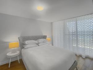 ein weißes Schlafzimmer mit einem Bett und einem Fenster in der Unterkunft Spacious Modern Apartment in Batemans Bay in Batemans Bay + 12 Fotos