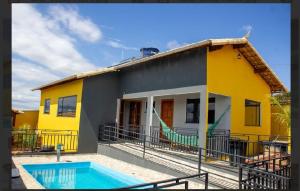 a yellow house with a swimming pool in front of it at Casa amarela in Santana do Riacho