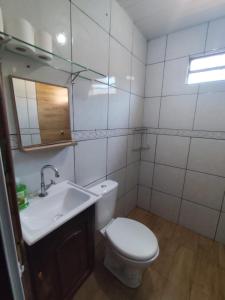 a bathroom with a toilet and a sink and a mirror at Casa Aconchego da Vó Gera in Foz do Iguaçu
