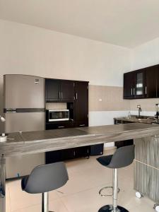 een grote keuken met een aanrecht en 2 barkrukken bij Moderna Casa Céntrica in Monterrey