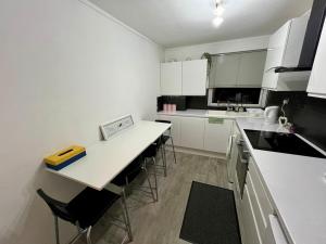 a kitchen with white cabinets and a table and chairs at Bright and Spacious 2 Bed Flat Sleeps 5 in Nottingham
