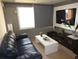 a living room with a black leather couch and a white coffee table at Agas Holiday Apartments Family in Tiberias