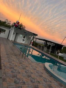 een zwembad voor een huis met een zonsondergang bij Finca Cimarrones Robles 