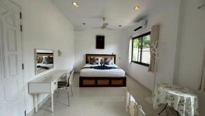 een slaapkamer met een bed, een bureau en een spiegel bij Lai Thai Villa 4 in Rawai Beach