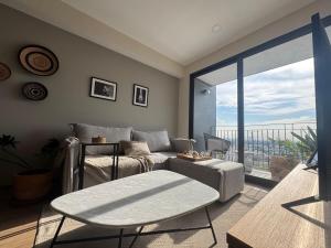 un soggiorno con un divano e una grande finestra di Depa - Estadio Guadalajara - Ciudad Judicial a Guadalajara