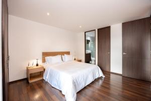 a bedroom with a white bed and a wooden floor at Apartamentos Casa Grande in Rionegro +49 photos