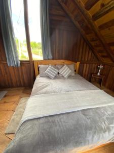 a large bed in a wooden room with a window at Cabana Rústica em Piedade in Piedade