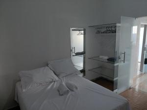 una camera da letto con un letto bianco e uno specchio di Kitnet Boa Vista a Sete Lagoas
