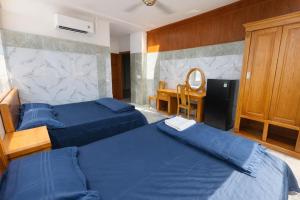 een slaapkamer met 2 blauwe bedden en een bureau bij Bình Minh Hotel Bình Dương in Xóm Bưng