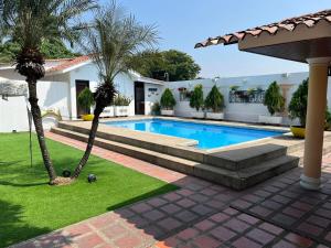 een zwembad met palmbomen naast een huis bij Hermosa Casa Colonial in SamborondÃ³n