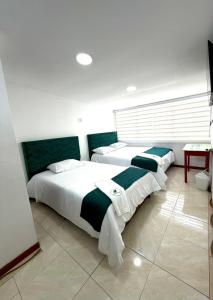 1 dormitorio con 2 camas con sábanas verdes y blancas en Hotel Hierbabuena y Restaurante, en Pasto