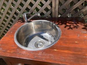ein Metallspülbecken mit Wasserhahn auf einer Holztheke in der Unterkunft Glamping with stunning sea view in Nelson