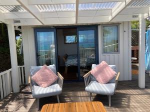 zwei Stühle und ein Tisch auf einer Veranda in der Unterkunft Glamping with stunning sea view in Nelson