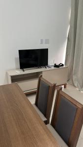 ein Wohnzimmer mit einem Tisch, einem Fernseher und Stühlen in der Unterkunft Casa térrea 2 suítes condomínio in Lauro de Freitas