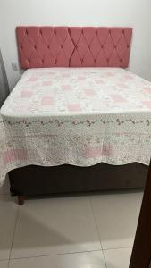 ein rosa Bett mit einer rosa-weißen Steppdecke in der Unterkunft Casa térrea 2 suítes condomínio in Lauro de Freitas