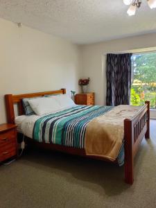 a bedroom with a large bed with a window at Cozy 1 安逸舒适小屋 in Christchurch