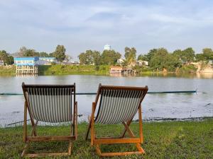 two chairs sitting next to a body of water at Merlin Hut & Farm in Kanchanaburi City