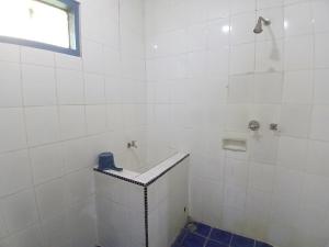 ein weiß gefliestes Bad mit einer Badewanne und einem Fenster in der Unterkunft Cibulan Indah Hotel in Brujul