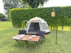 a tent with a table and chairs in a field at Merlin Hut & Farm in Kanchanaburi City +49 photos