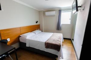 a small bedroom with a bed and a window at Hotel Move BH in Belo Horizonte