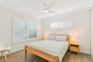 a white bedroom with a bed and two lamps at Endless Horizon in Kingscliff