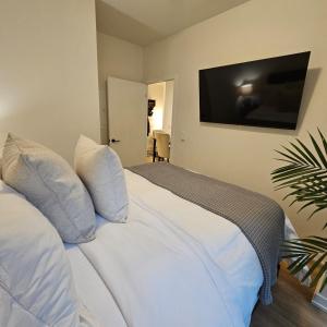 Schlafzimmer mit einem weißen Bett und einem Flachbild-TV in der Unterkunft Stockyards in Toronto