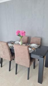 ein Esstisch mit Stühlen und einer Vase mit Blumen in der Unterkunft Kempinski Apartment in Jakarta