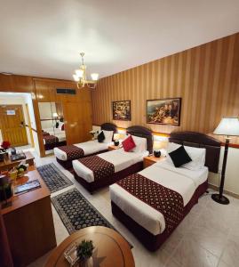 a hotel room with three beds and a table at Golden California Hotel in Dubai