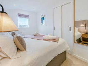 een witte slaapkamer met een bed en een spiegel bij Lodge 52 Una in Carbis Bay +35 foto's