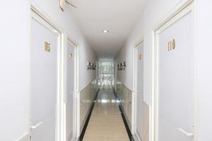 a hallway with white walls and floors and doors at Urbanview Hotel DHelomi Homestay near UPN Veteran in Kalasan +31 photos