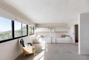 een witte slaapkamer met een stapelbed en ramen bij Absolute Beachfront House with Pool & Views in Marcus Beach