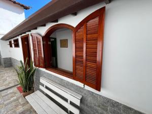 una casa con contraventanas de madera en un lateral en Excelente casa com garagem no centro de Búzios!, en Búzios