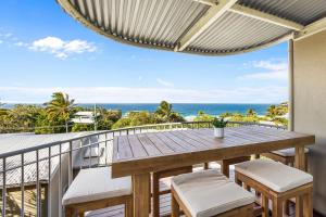 eine Terrasse mit einem Holztisch und Stühlen auf dem Balkon in der Unterkunft 8 Andari Sunshine Luxury 1min to Beach in Sunshine Beach