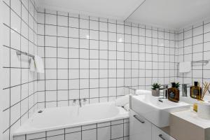 Ein weiß gefliestes Badezimmer mit zwei Waschbecken und einer Badewanne in der Unterkunft 8 Andari Sunshine Luxury 1min to Beach in Sunshine Beach