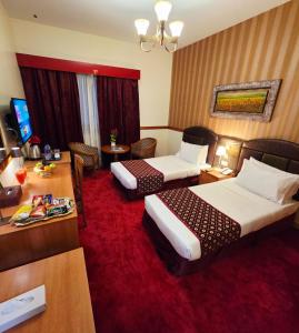 a hotel room with two beds and a desk at Golden California Hotel in Dubai