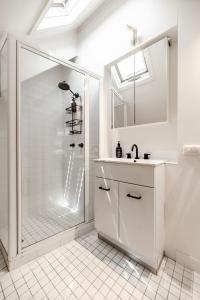 Un baño blanco con ducha y lavabo. en The Rest Family Cottage with Resort Style Pool, en Noosa Heads
