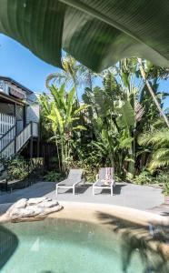 un patio con dos sillas y una piscina en The Rest Family Cottage with Resort Style Pool, en Noosa Heads