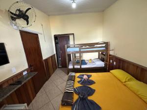 a bedroom with two bunk beds and a tv at Suítes Pouso do Sol in Praia de Araçatiba