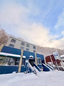 een blauw gebouw met sneeuw ervoor bij Powder Base Naeba in Yuzawa