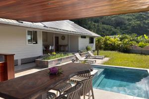 a patio with a wooden table and chairs next to a pool at Villa Noa Vai in Hauru