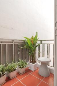 ein Balkon mit Topfpflanzen, einem Tisch und einer Bank in der Unterkunft Lebatriu in Hanoi