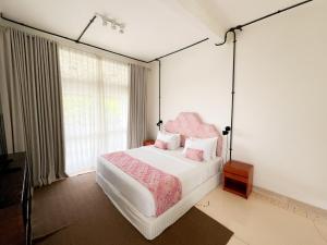 a bedroom with a large bed with a pink headboard at Kresna By The Sea By Kresna Hospitality in Seminyak +150 photos