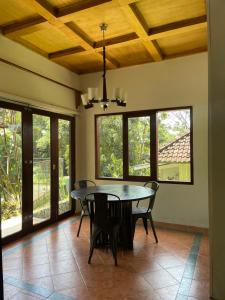 ein Esszimmer mit Tisch und Stühlen und Fenstern in der Unterkunft Covehill Green Resort in Pelabuhan Ratu