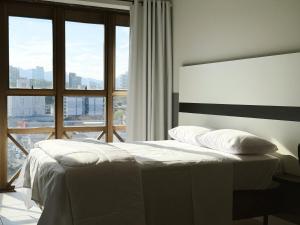 a white bed in a room with a large window at Smart Stay Lofts in Joinville +233 photos
