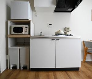 a kitchen with white cabinets and a microwave at Home Story in Tokyo Ueno&Uguisudani-小島ビル&東京屋語 in Tokyo