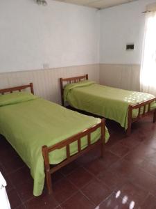 2 letti in una camera con lenzuola verdi di La casita a Pringles
