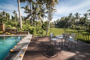 a patio with a table and chairs next to a swimming pool at Serenity Villa & Spa in Ubud