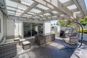 een terras met luifel, een bank en een schommel bij Seven Miles Beach Escape in Shoalhaven Heads