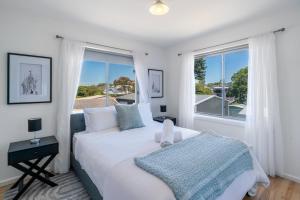 een witte slaapkamer met een bed en een raam bij Seven Miles Beach Escape in Shoalhaven Heads +29 foto's